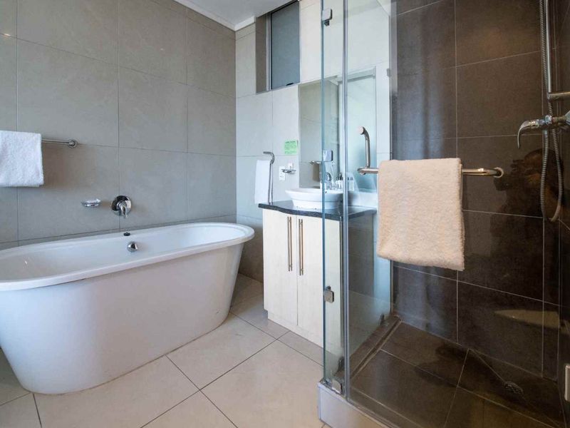 Modern bathroom featuring a sleek freestanding bathtub, a separate glass-enclosed shower, and a vanity with a vessel sink and tiled finishes.