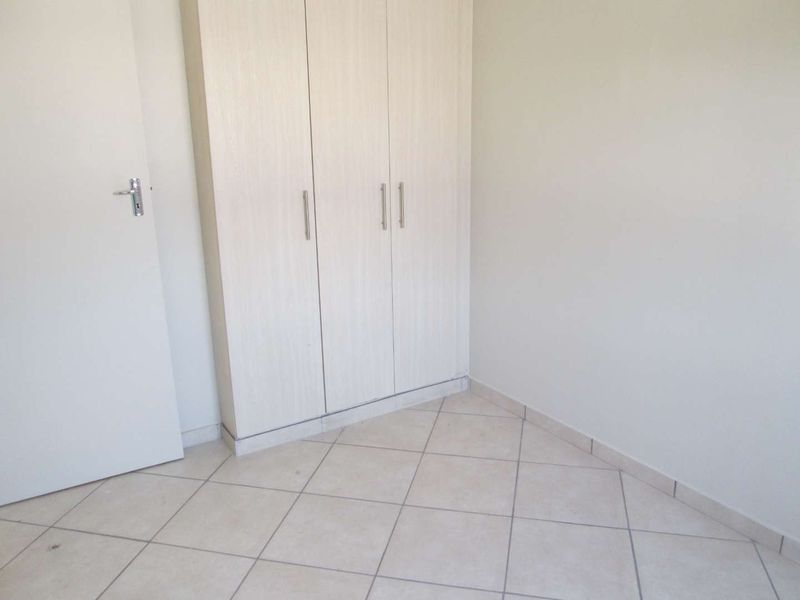 A clean, empty bedroom featuring neutral tiled flooring and built-in cupboards, providing a blank canvas for personalization.