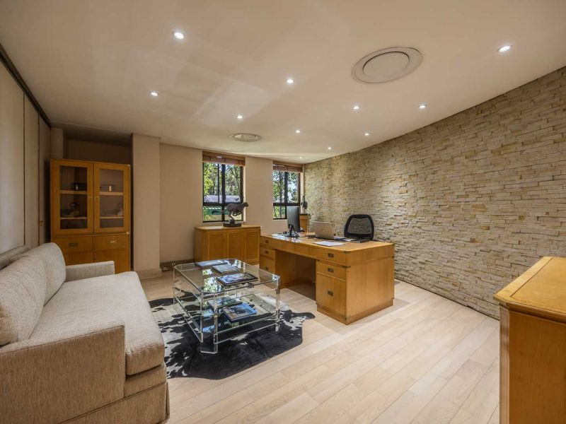 A well-appointed office space featuring a textured stone feature wall, recessed downlighting, and light timber flooring, creating a professional and inviting work environment.