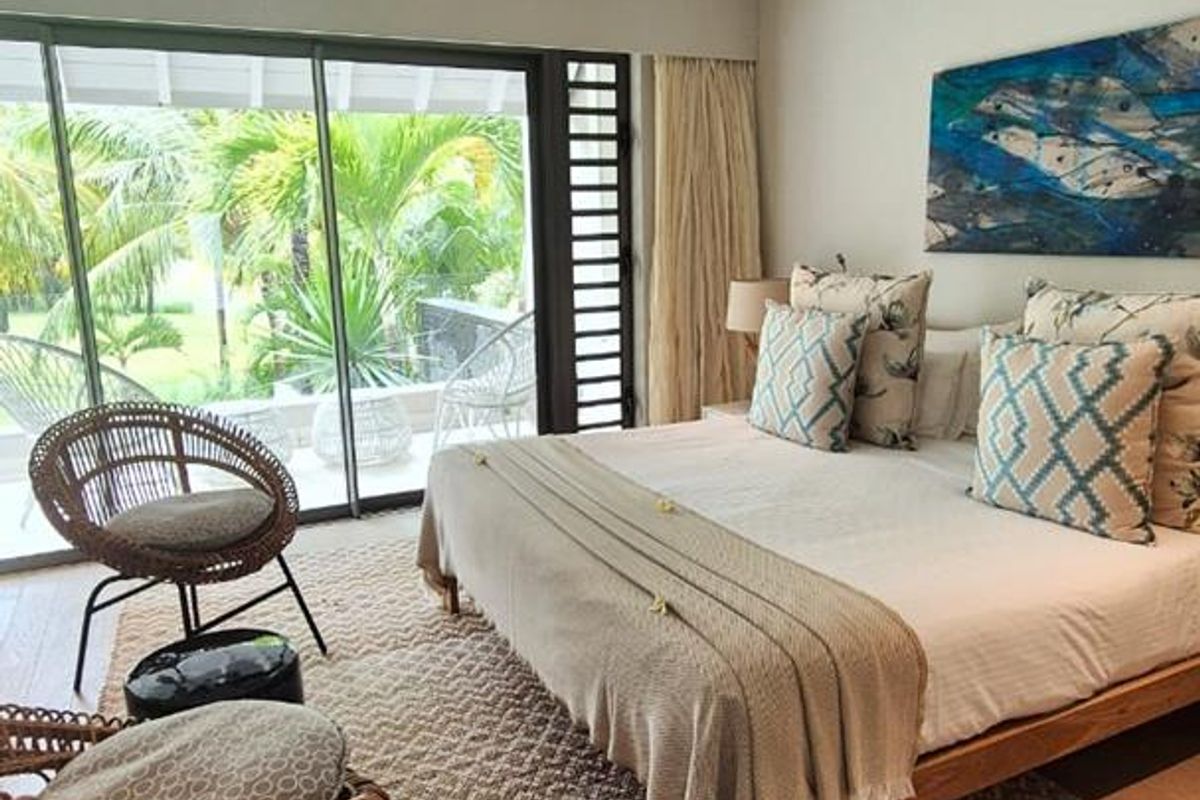 A bright and airy bedroom featuring large sliding glass doors that open to a private patio, complemented by a ceiling fan and wall-mounted air conditioning.