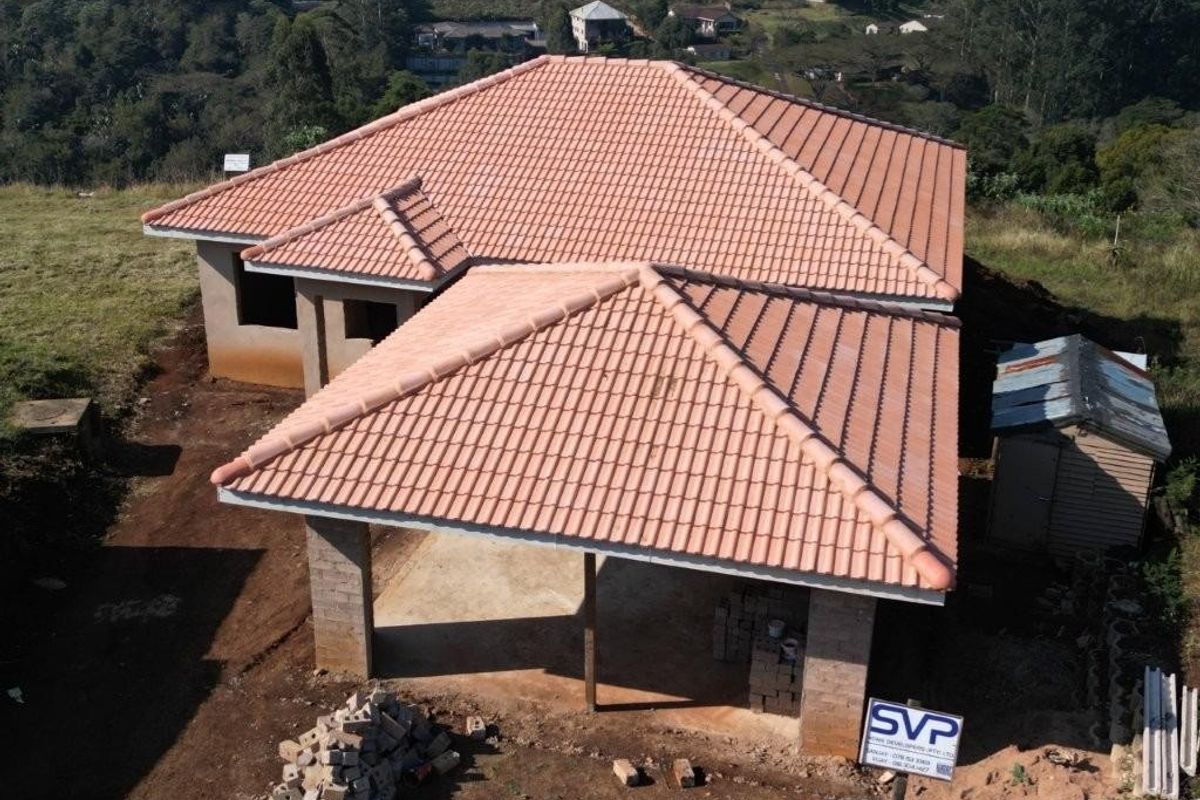 Aerial view of a residential property under construction, featuring a completed tiled roof and unfinished exterior structure.