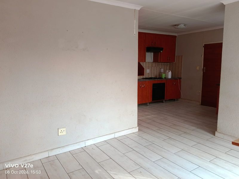 Open plan living area featuring tiled flooring and a compact kitchen with built-in cabinetry, oven, and extractor fan.