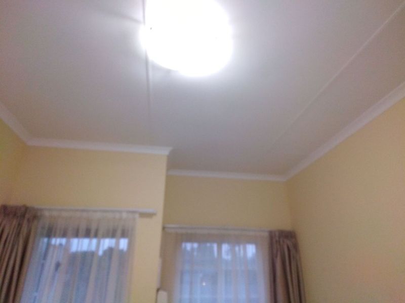 A view of a bedroom ceiling featuring a flush mount light fixture and decorative cornice detailing.