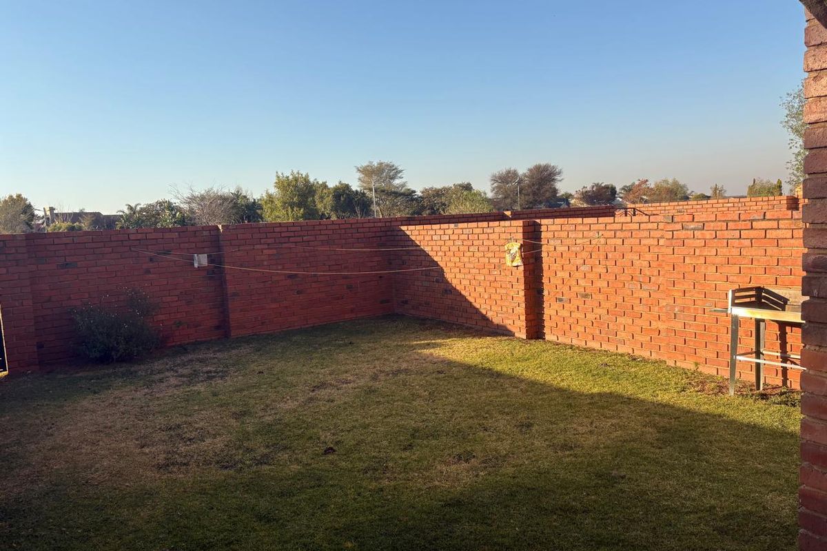A private rear garden featuring a well-defined lawn area enclosed by sturdy face-brick perimeter walls.