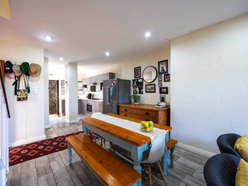 Open-plan living and dining area featuring tiled flooring, recessed lighting, and a functional kitchen with built-in cabinetry and appliances.