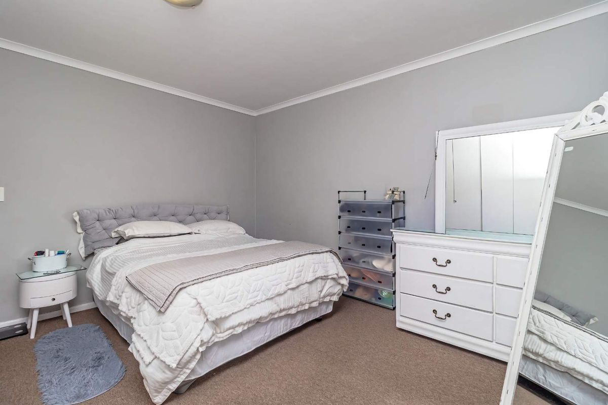 A neutrally painted bedroom featuring carpeted flooring, coving, and built-in wardrobe storage.