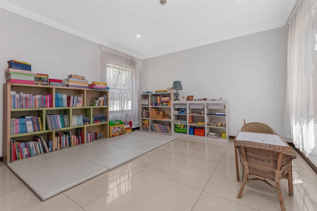 A bright bedroom featuring large format floor tiles, recessed downlighting, and coved cornicing, currently utilized as a play and study area.
