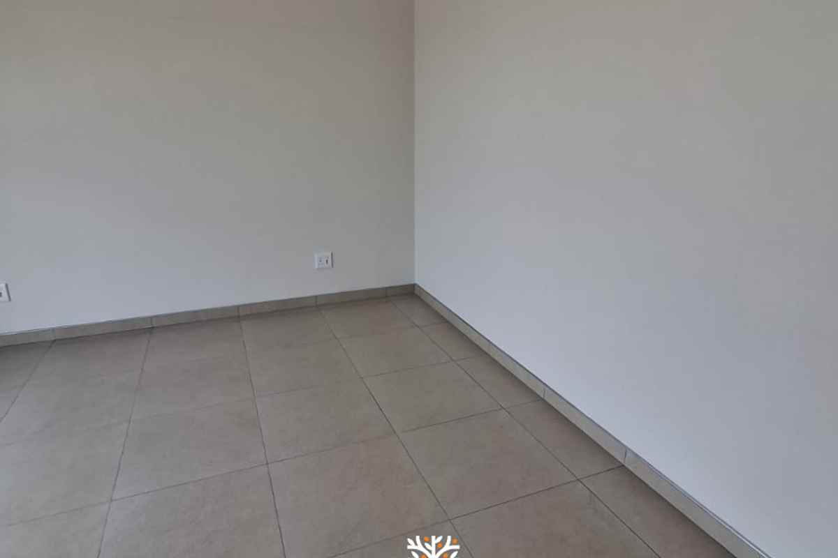 A clean, empty room featuring neutral ceramic floor tiles and plain painted walls, providing a versatile blank canvas for any living space.