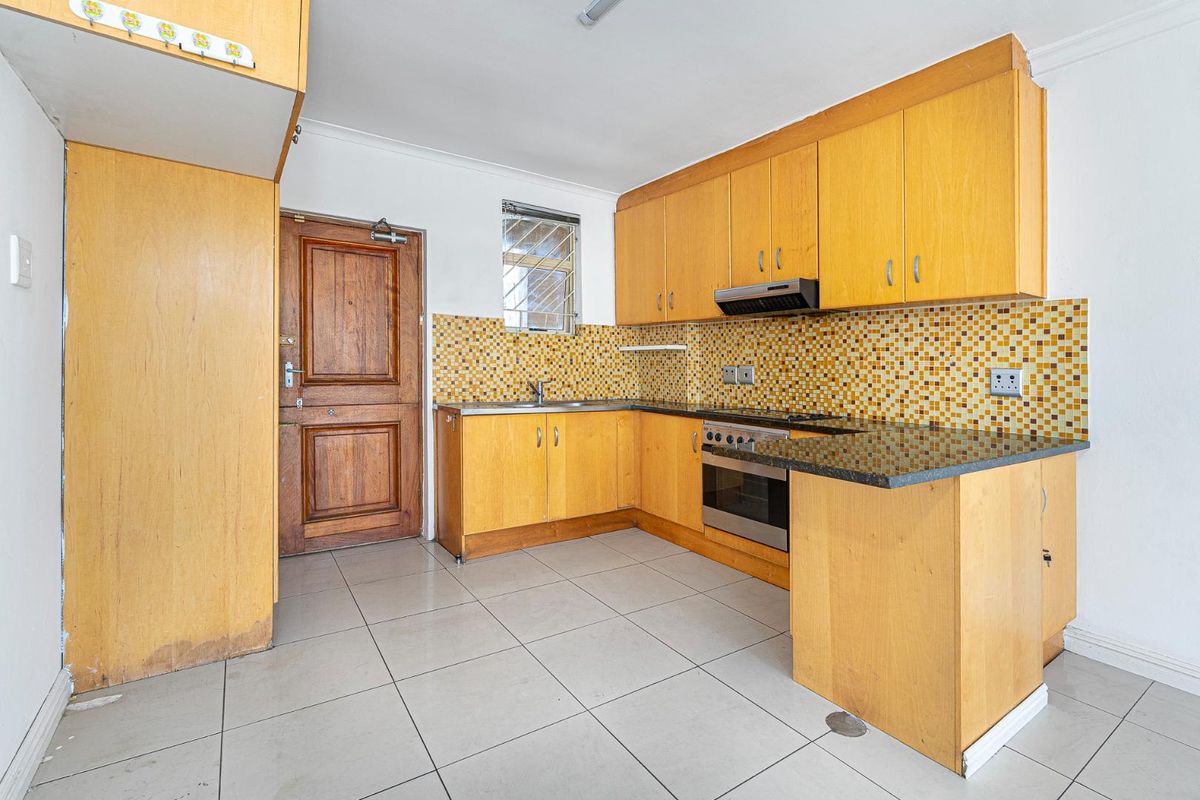 Functional kitchen featuring light wood cabinetry, granite countertops, a built-in oven with extractor fan, and a mosaic tile backsplash.
