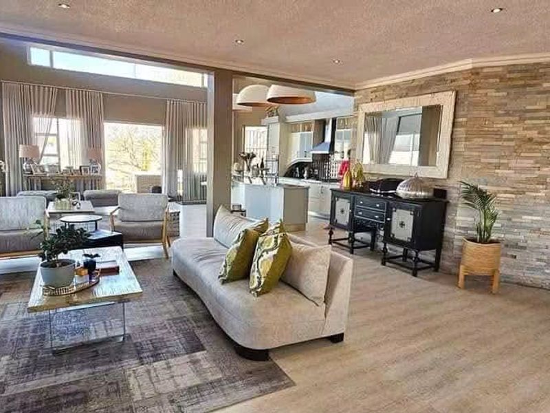 Spacious open-plan living area featuring a stone accent wall, modern fireplace, and large windows that provide ample natural light.