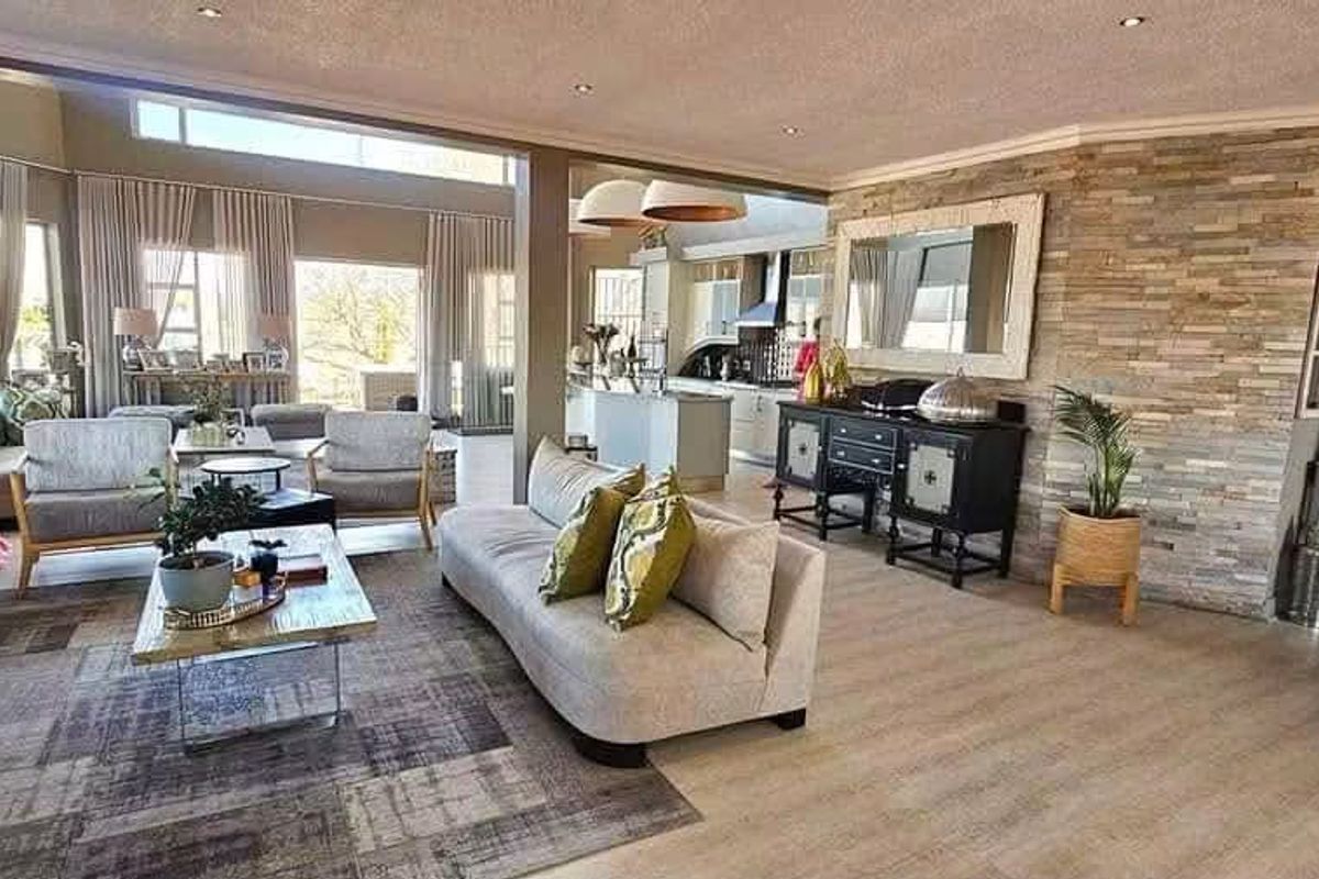 Spacious open-plan living area featuring a stone accent wall, modern fireplace, and large windows that provide ample natural light.