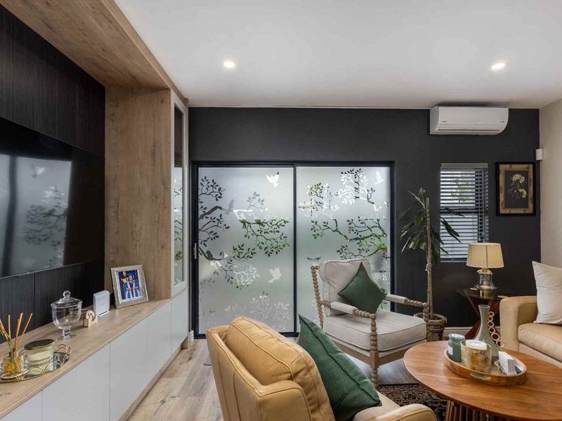Modern living room featuring custom built-in cabinetry, split-system air conditioning, recessed lighting, and a sliding glass door with decorative frosted film.