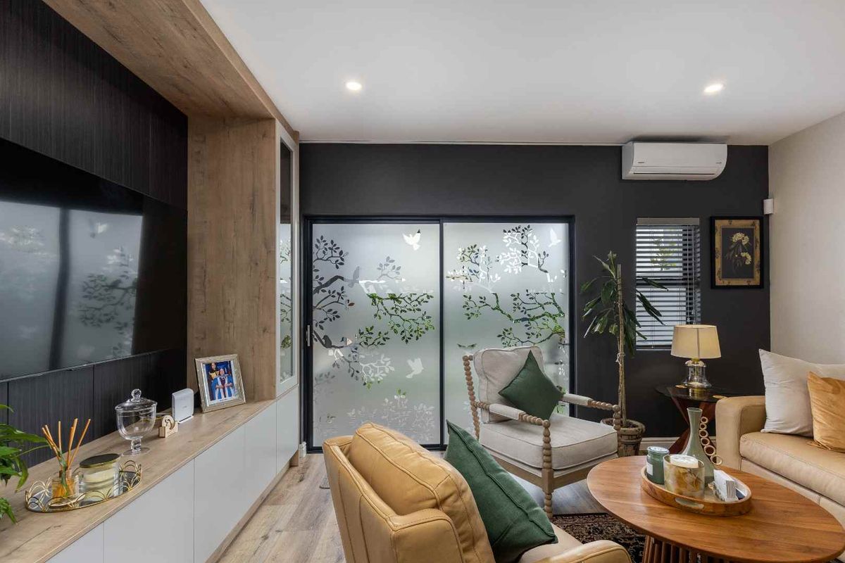 Modern living room featuring custom built-in cabinetry, split-system air conditioning, recessed lighting, and a sliding glass door with decorative frosted film.