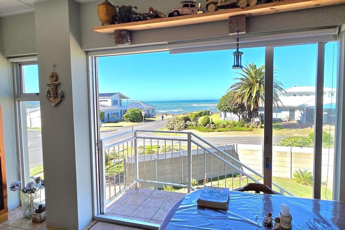 A bright living area featuring large sliding glass doors that open onto a balcony with scenic coastal and neighbourhood views.