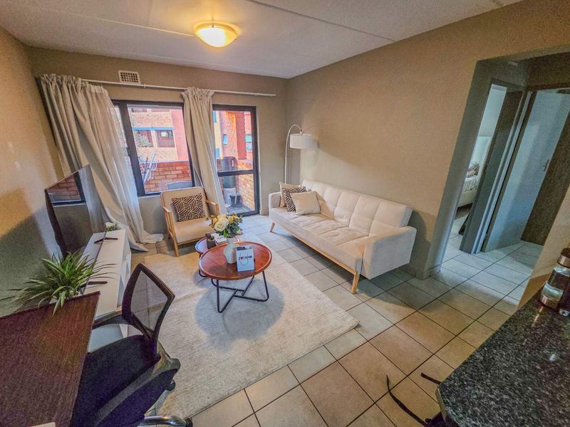 A functional living room featuring tiled flooring and a sliding glass door providing access to an outdoor area.