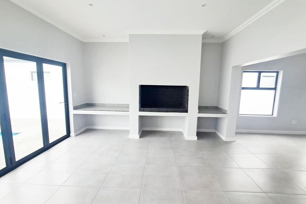 Spacious living area featuring a built-in fireplace, tiled flooring, recessed lighting, and large glass sliding doors leading to the outdoor space.