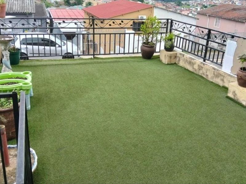 An elevated balcony area featuring artificial turf flooring and a decorative wrought iron safety railing, offering an open outdoor space.