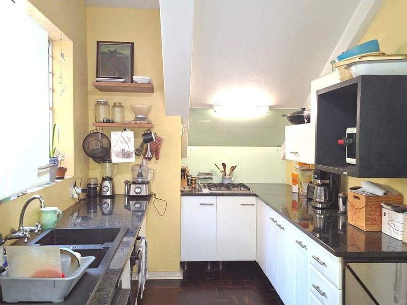 Compact kitchen featuring granite countertops, white cabinetry, a built-in gas hob, and an undermount sink with a modern mixer tap.