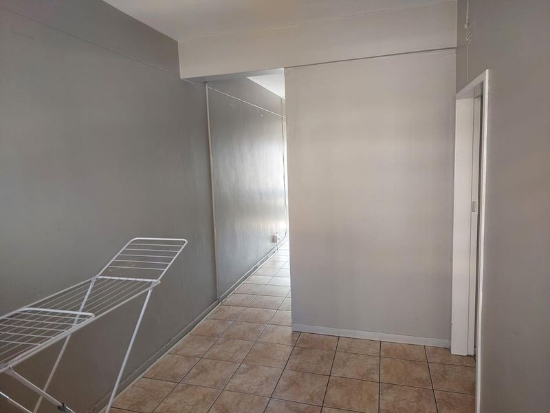 A functional hallway featuring neutral grey walls and tiled flooring, providing a clean and simple transition space within the apartment.