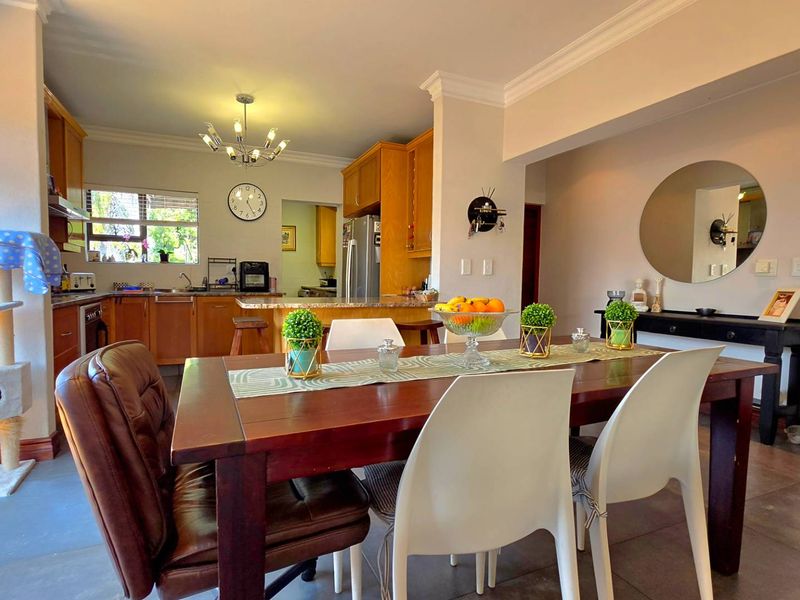 Open-plan living and dining area featuring a functional kitchen with wooden cabinetry, granite countertops, and tiled flooring throughout.