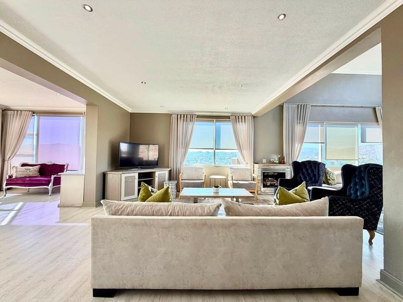 Spacious open-plan living area featuring recessed lighting, crown molding, a fireplace, and large windows with scenic views.
