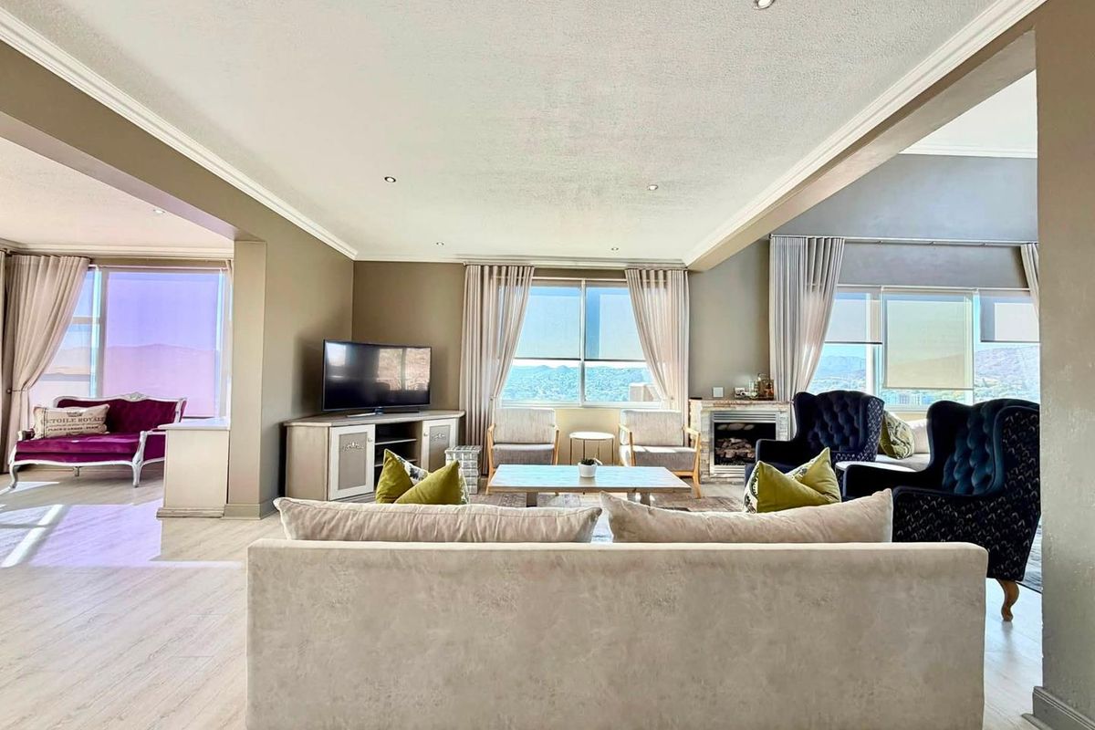 Spacious open-plan living area featuring recessed lighting, crown molding, a fireplace, and large windows with scenic views.