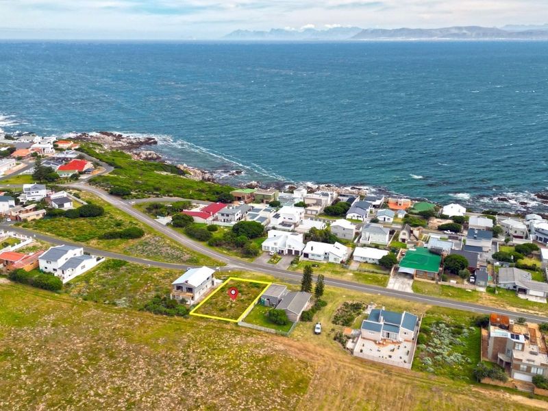 Aerial view of a vacant residential plot situated in a coastal neighborhood with ocean views.
