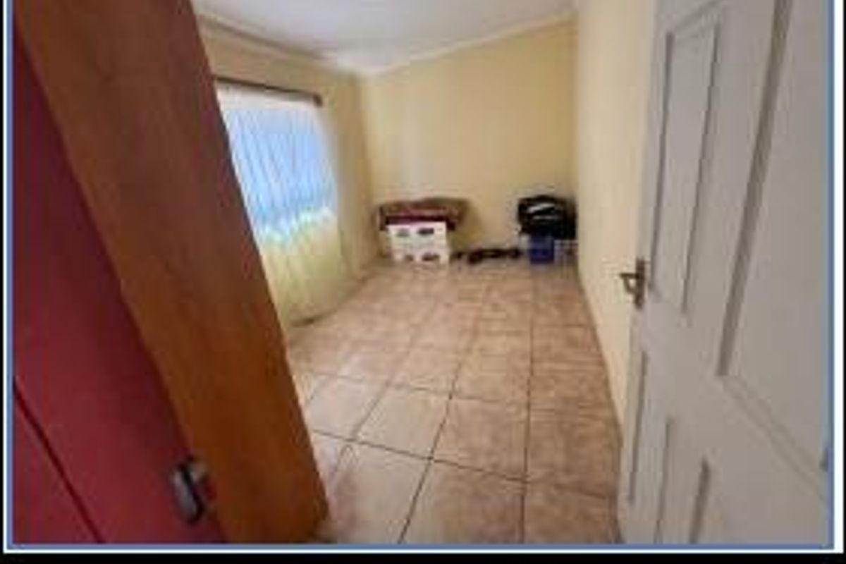 A functional bedroom featuring tiled flooring and a standard door entrance, offering a blank canvas for personalization.