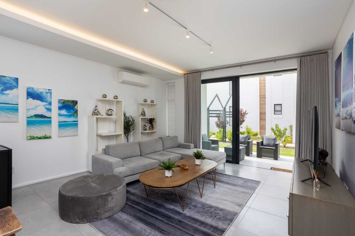 Modern living room featuring tiled floors, recessed ceiling lighting, and a large sliding glass door providing seamless access to the outdoor patio area.
