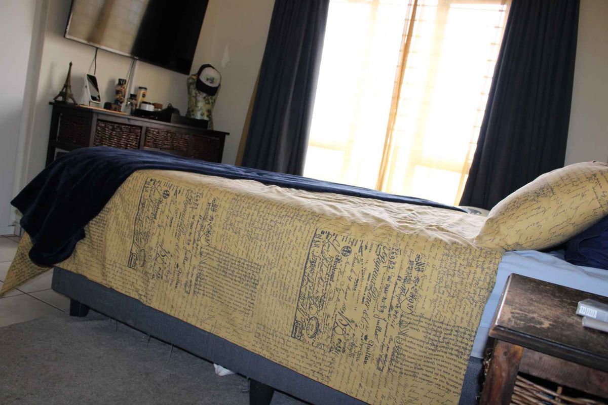 A bedroom featuring tiled flooring and a window with curtain tracks, showing minor wall surface wear.
