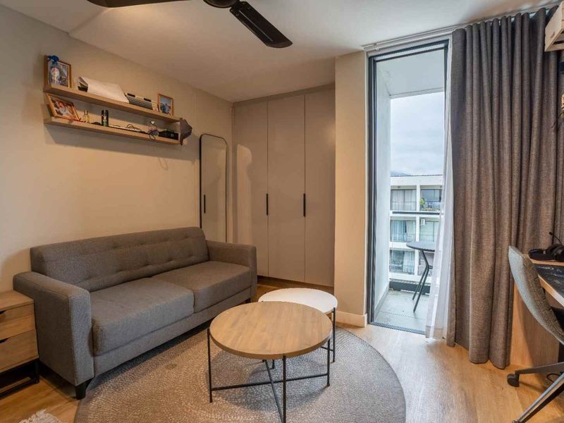 A well-maintained living area featuring built-in cabinetry, a ceiling fan, and direct access to a private balcony through a sliding glass door.