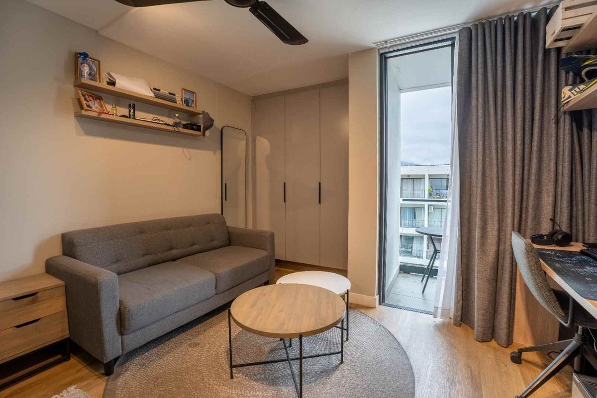 A well-maintained living area featuring built-in cabinetry, a ceiling fan, and direct access to a private balcony through a sliding glass door.