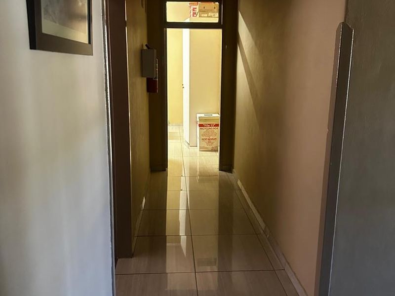 A functional interior hallway featuring neutral wall tones and polished tiled flooring, providing access to adjacent rooms.