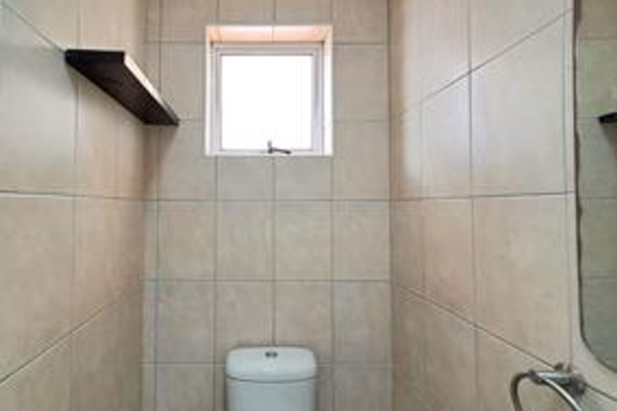 A compact bathroom featuring full-height wall tiling, a modern toilet, and a wall-mounted towel ring.