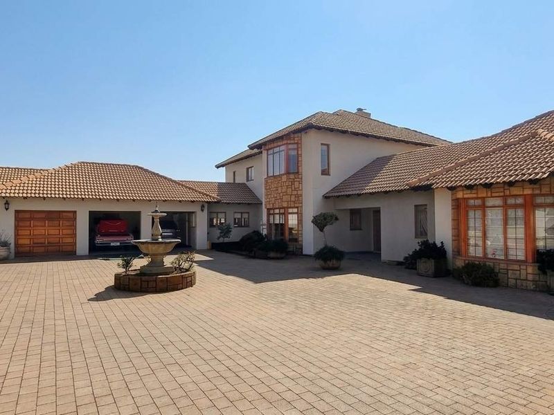 Spacious front exterior featuring a large paved driveway, triple garage, and a central water fountain, showcasing a well-maintained residential facade.