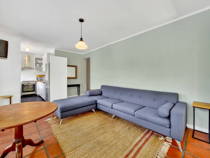 Open-plan living area featuring terracotta floor tiles and a functional kitchen with built-in oven and stainless steel extractor fan.