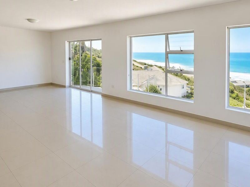Spacious, light-filled living area featuring polished porcelain tile flooring and large windows offering expansive coastal and ocean views.