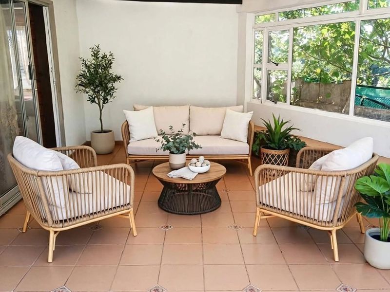 A covered patio area featuring tiled flooring, exposed timber beams, and large windows, providing a bright and functional outdoor living space.