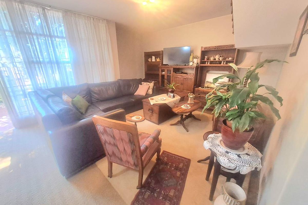 A comfortable living room featuring neutral carpeting and a large window that allows for natural light, providing a versatile space for relaxation.