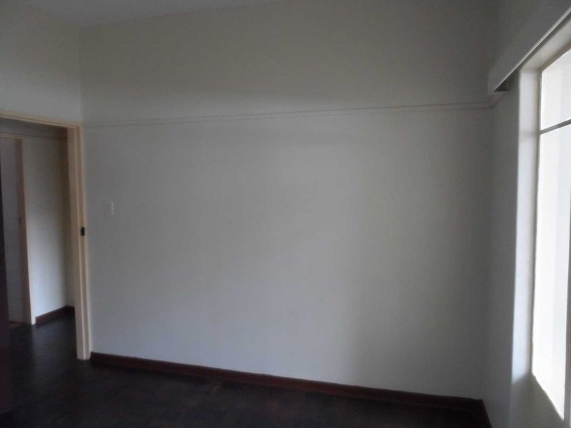 An empty bedroom featuring dark timber flooring, neutral walls, and a classic picture rail, offering a blank canvas for interior design.