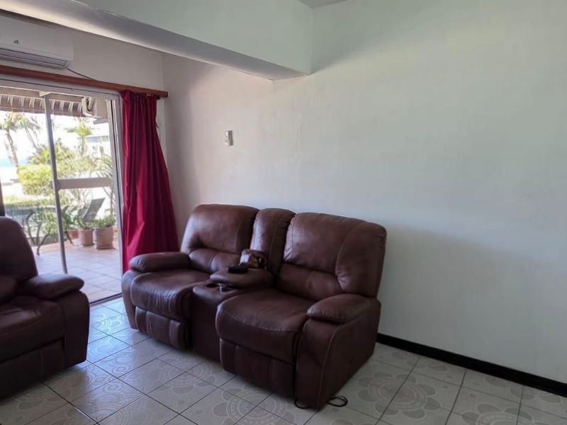 Living room featuring ceramic tiled flooring, a wall-mounted air conditioning unit, and a sliding glass door providing access to an outdoor patio area.