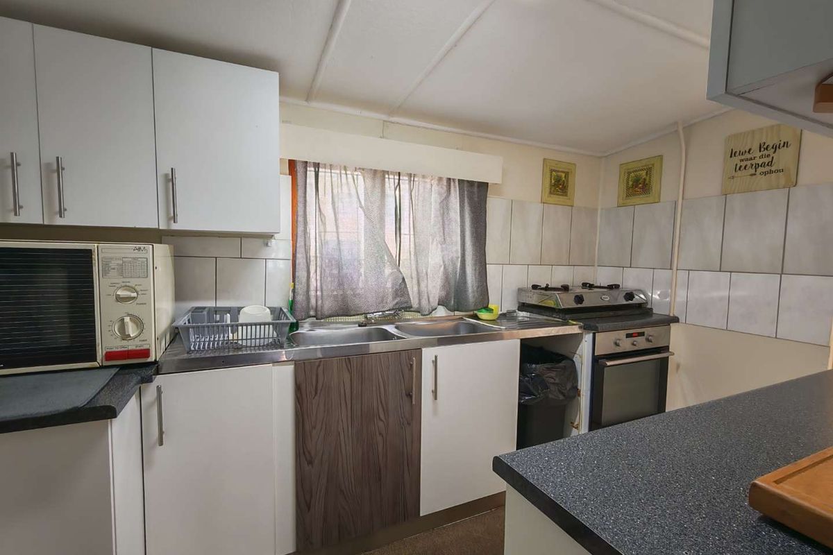 A functional kitchen featuring built-in cabinetry, a stainless steel sink, tiled backsplash, and a built-in oven with a gas hob.