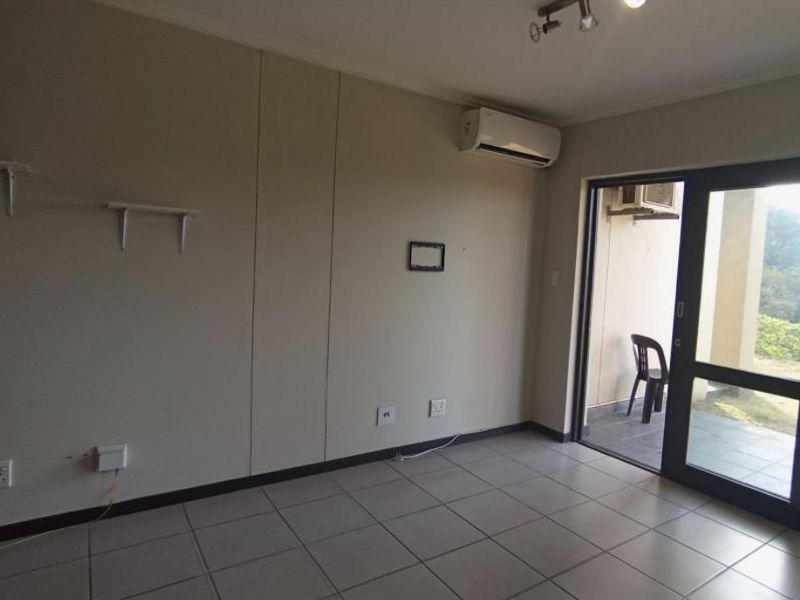An empty living room featuring tiled flooring, an air conditioning unit, and a sliding glass door providing access to an outdoor patio area.