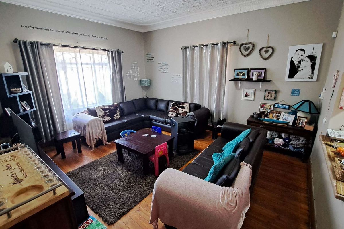 A spacious living room featuring original timber flooring, decorative ceiling cornices, and large windows that provide ample natural light.