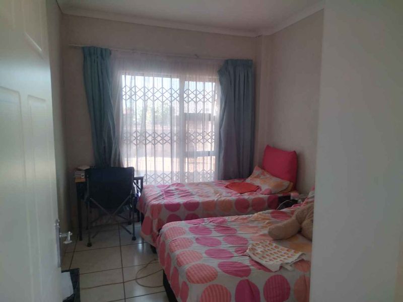 A bedroom featuring tiled flooring and a sliding glass door with an integrated security gate.