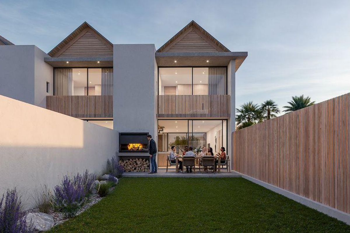 Rear view of a modern townhouse featuring a private garden, built-in braai area, timber fencing, and upper-level balcony with sliding glass doors.