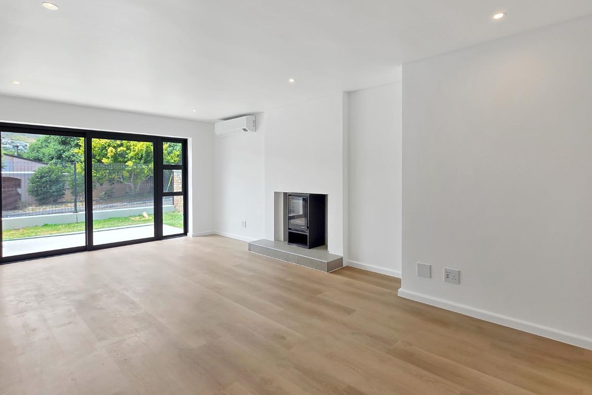 Bright and spacious living area featuring light wood-look flooring, a modern built-in fireplace, air conditioning unit, and large sliding glass doors leading outdoors.