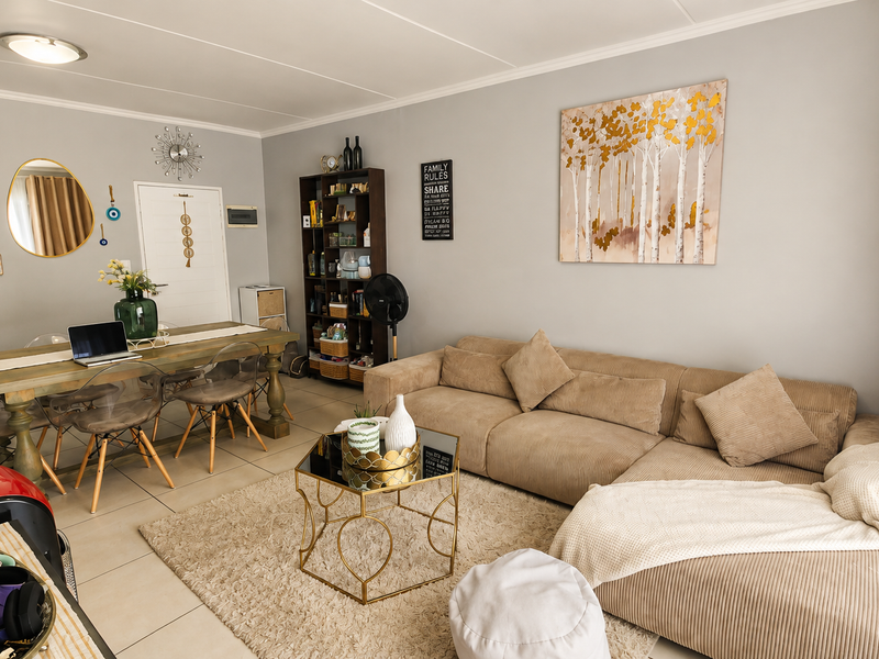 A bright open-plan living and dining area featuring neutral wall tones and tiled flooring, providing a versatile space for relaxation and entertaining.
