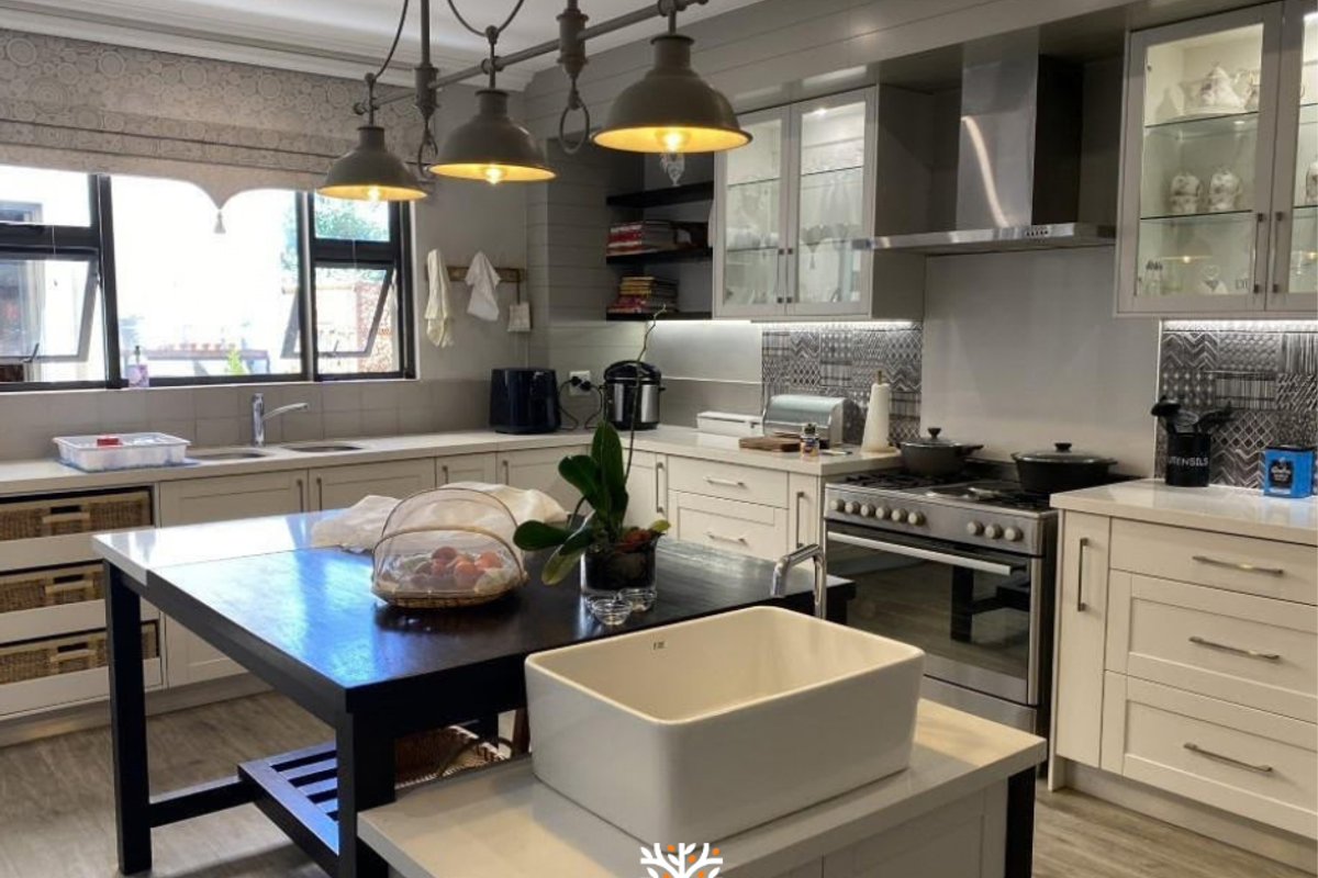 Modern kitchen featuring a large central island, farmhouse sink, gas stove with extractor, and high-quality cabinetry with stone countertops.