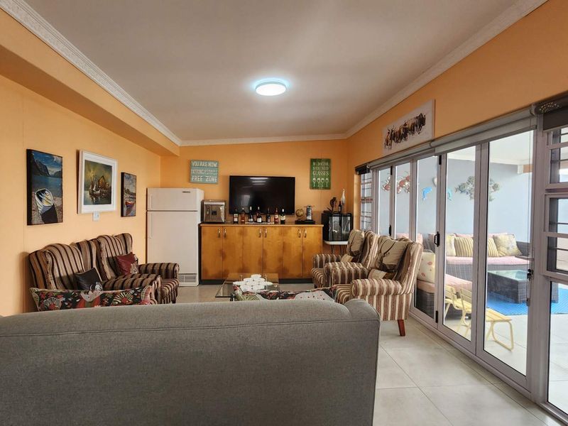 Spacious living room featuring tiled flooring, crown molding, and large sliding glass doors that provide seamless access to the outdoor patio area.